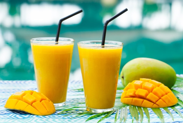 Fresh tropical fruit smoothie mango juice and fresh mango on a outdoor tropical background