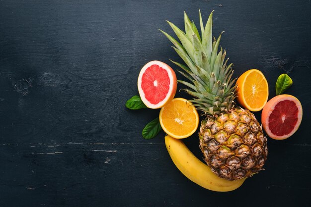 Fresh Tropical Fruits Coconut pineapple kiwi and grapefruit On a wooden background Top view Free space for text