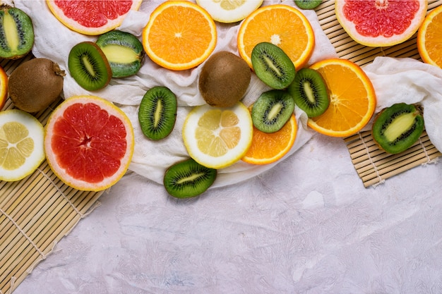 Fresh Tropical Fruits, Grapefruit, Lemon, Orange, Kiwi on a Light Stone Background.