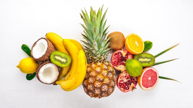 Fresh Tropical Fruits Pineapple coconut kiwi orange pomegranate grapefruit On a wooden background Top view Free space for text