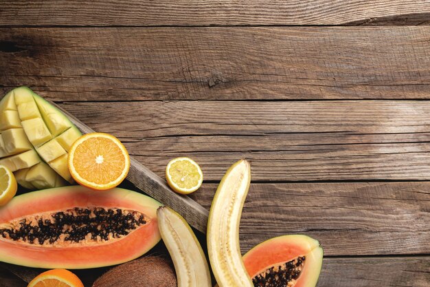 Fresh tropical fruits in a wooden box on a wooden background