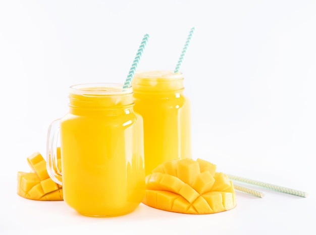 Fresh tropical mango juice with beautiful diced pulp and striped paper straw isolated on white background table close up cut out clipping path