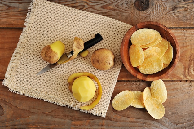 Fresh tubers of potato, knife for cleaning of potatoes and potato chips