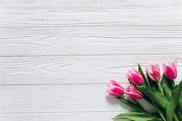 Fresh tulips bouquet on a white wooden background. Mothers day concept, top view.