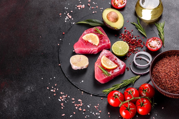 Fresh tuna fillet steaks with spices and herbs on a black.