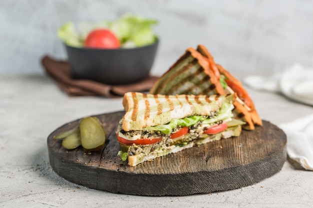 Свежий сандвич тунца, томата, соленья и салата на крупном плане здравицы хлеба на деревянной доске.