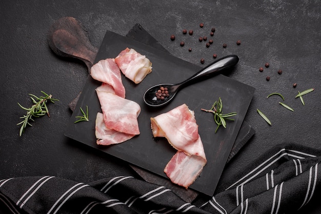 Photo fresh uncooked bacon on wooden board with spoon and herbs