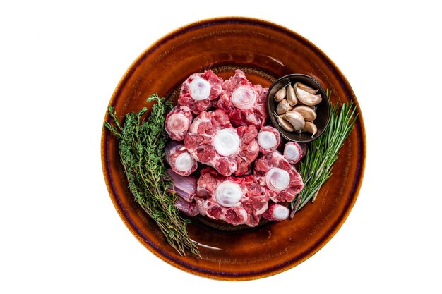 Photo fresh uncooked beef oxtail cut meat on rustic plate with herbs isolated on white background