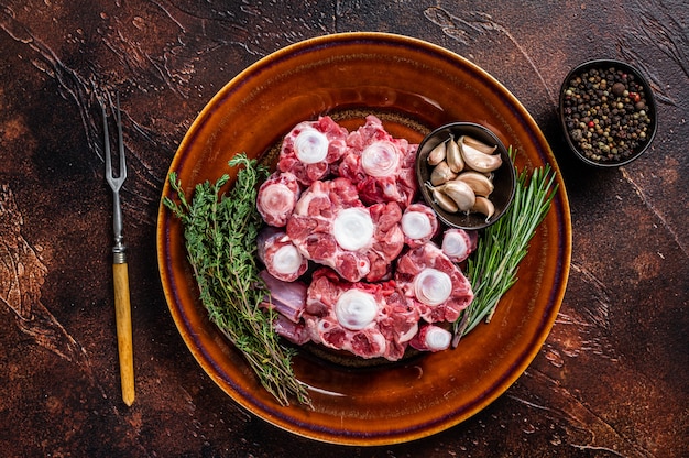 Fresh uncooked beef Oxtail cut Meat on rustic plate with herbs