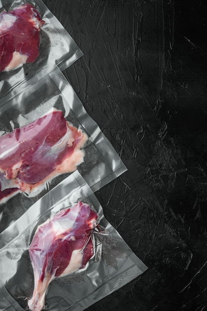 Fresh uncooked duck meat legs and breast vacuum sealed on black stone