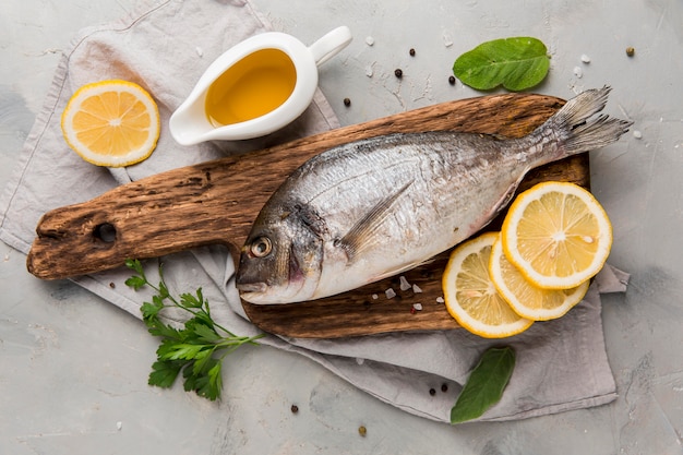 Photo fresh uncooked fish on wooden board with lemon slices