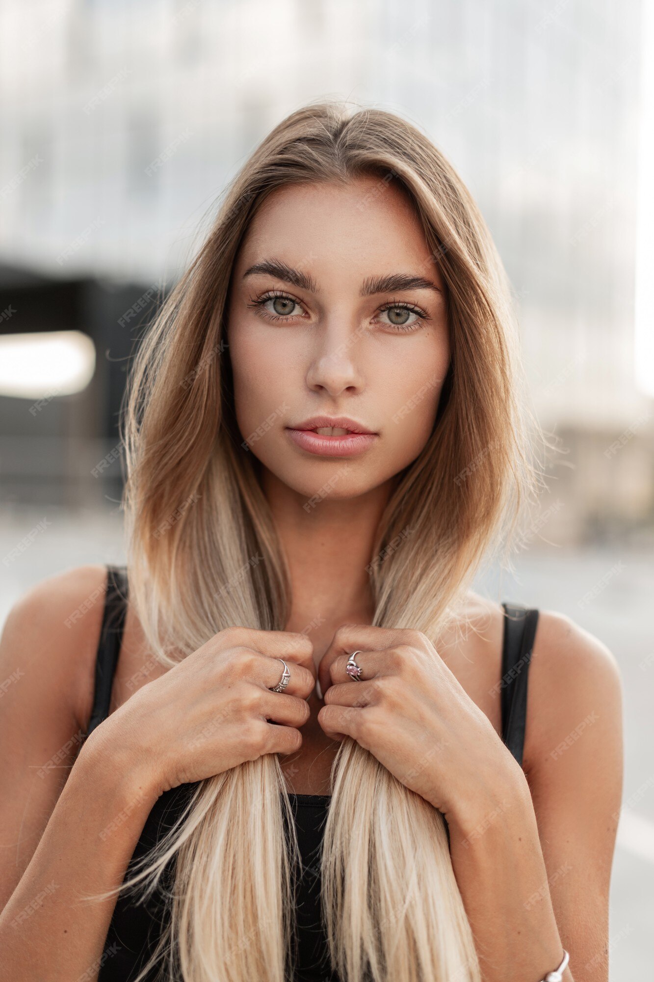 Premium Photo | Fresh urban portrait of beautiful young woman model with green  eyes holding beautiful blonde hair in the city and looks at the camera