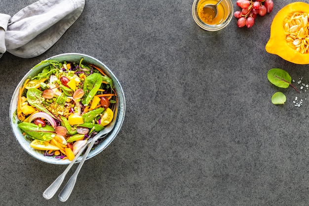 Fresh vegetable and fruit salad in a plate on black stone. Top view