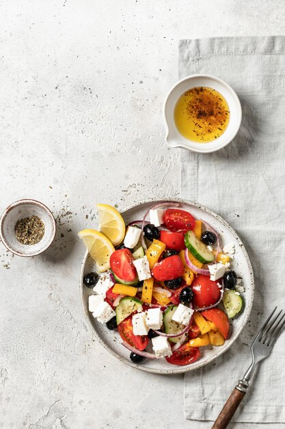 Fresh vegetable greek salad on a light textured table with fork Top view