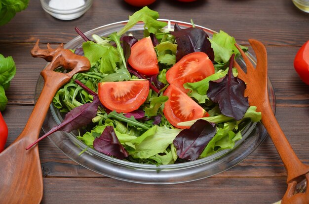 Fresh vegetable salad in a plate and beautiful wooden cooking utensils close up