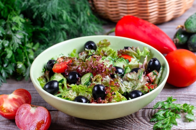 Салат из свежих овощей с оливками в миске