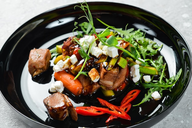 Fresh vegetable salad with veal zucchini veal feta cheese and arugula On a black plate Rustic style