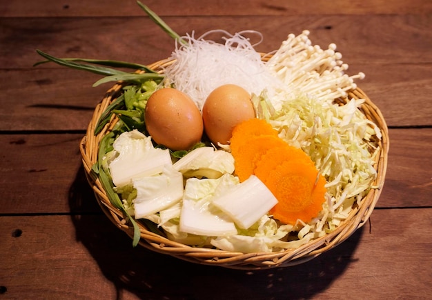 Fresh Vegetable Set Morning Glory Chinese Cabbage Carrot Sliced Cabbage and golden needle mushroom with 2 fresh eggs and Bean vermicelli Place in a basket on a wooden table