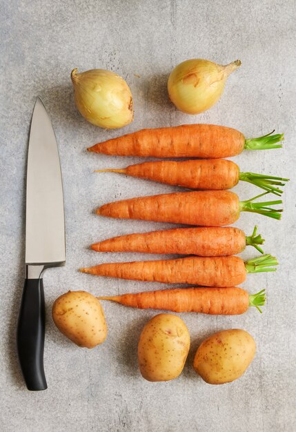 Fresh vegetables and a chefs knife are on the table, top view