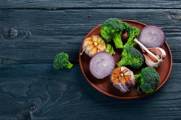 Fresh vegetables on a clay plate On a wooden background Top view Free space for your text