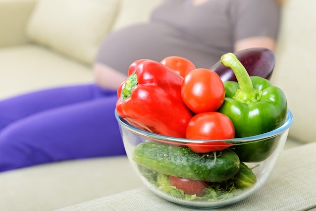 Fresh vegetables on the couch next to a pregnant woman