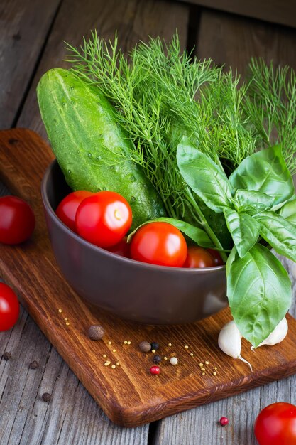 Fresh vegetables: cucumbers, tomatoes, basil and dill in a bowl