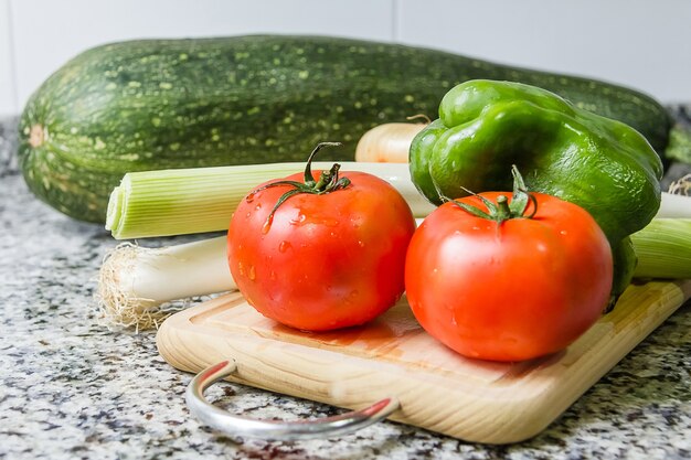 Photo fresh vegetables on cutting board in the kitchen over granite worktop