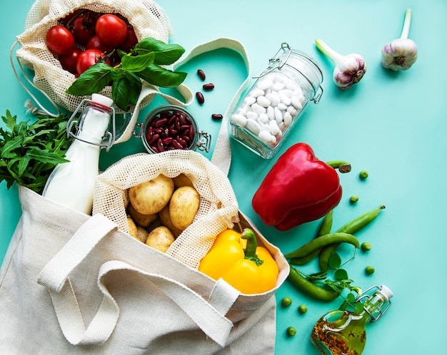 Photo fresh  vegetables in eco cotton bags on green background.  zero waste shopping concept.