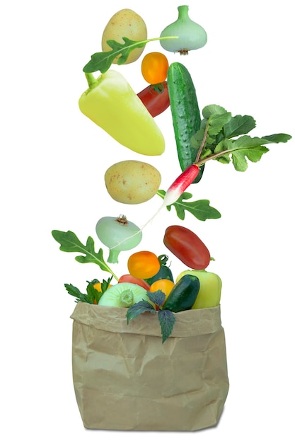 Свежие овощи попадают в крафт-пакет, изолированный на белом фоне