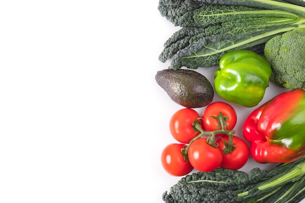 Fresh vegetables frame. black kale leaves, tomatoes branch, red and green bell pepper, avocado