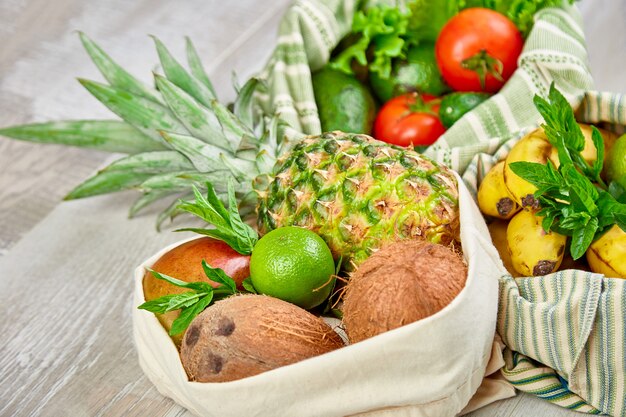 Fresh vegetables and fruits in eco cotton bags on table in the kitchen