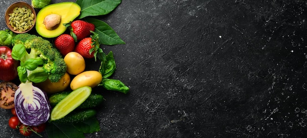 Fresh vegetables and fruits fennel avocado pomegranate berries cabbage and basil Organic healthy vegan food On a black stone background