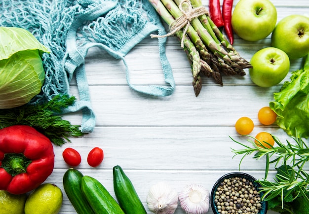 Fresh vegetables and fruits with a string bag on a white wooden surface. Healthy lifestyle. Top view. Zero waste.