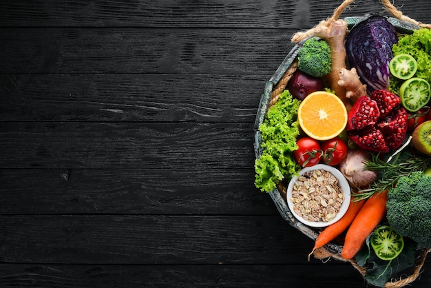 Fresh vegetables and fruits in a wooden box on a black background Organic food Top view Free copy space