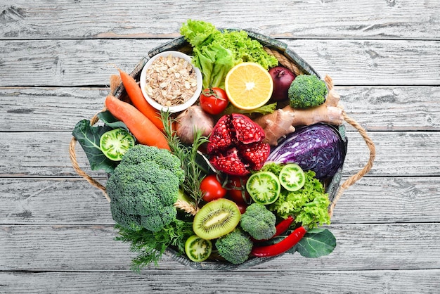 Fresh vegetables and fruits in a wooden box on a white wooden background Organic food Top view Free copy space