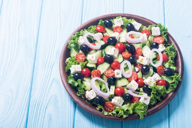 Греческий салат из свежих овощей. Здоровая еда на деревянном фоне.