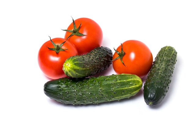 Fresh vegetables green cucumbers and red tomatoes on white isolated background, closeup. Healthy diet, vegetarian food