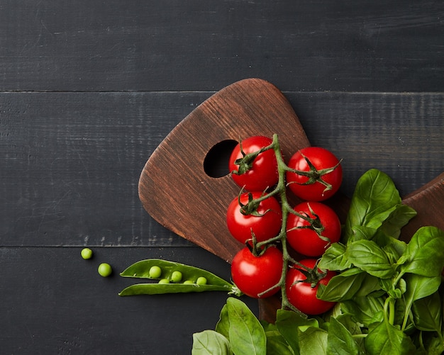 Fresh vegetables and herbs on a dark wooden background. Space for text and flat lay. Vegan concept