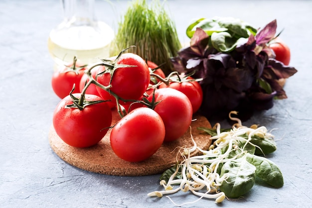 fresh vegetables and herbs Fresh red tomatoes are lying on wooden board Leaves of spinach and basil