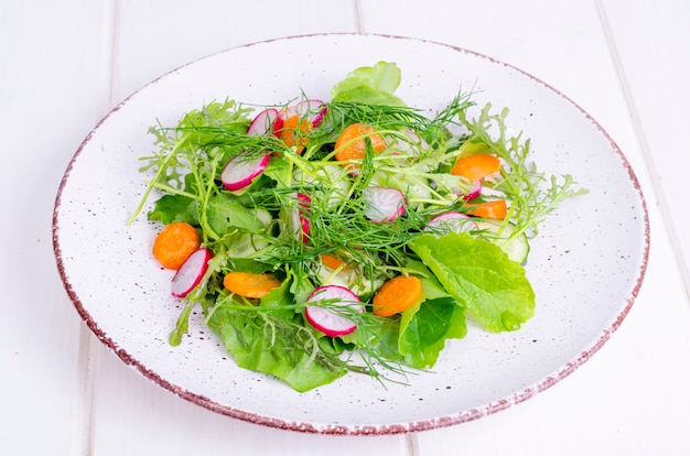 Fresh vegetables and leaves of green salads on white plate