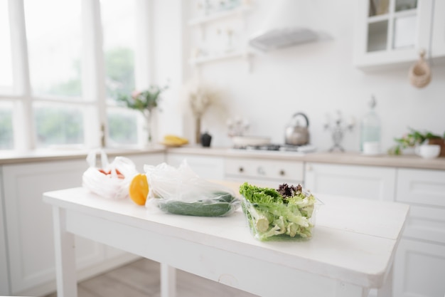 白い木製のキッチンテーブルに新鮮な野菜とレタス