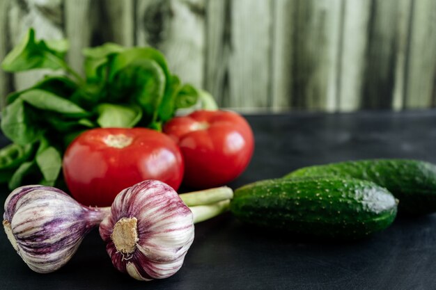 Photo fresh vegetables like tomatoes and cucumbers near garlic