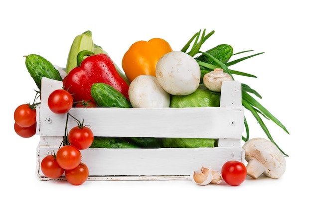 Fresh vegetables in a painted wooden box isolated on white background