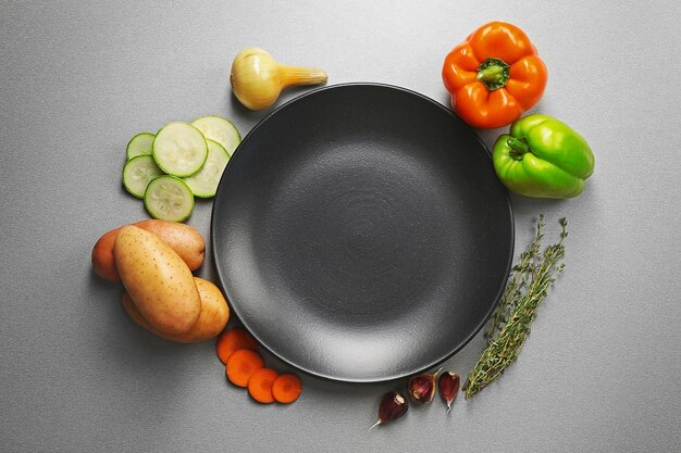 Photo fresh vegetables and plate on grey textured background