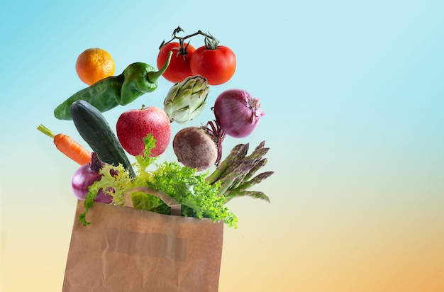 背景から分離されたリサイクル可能な紙袋に新鮮な野菜