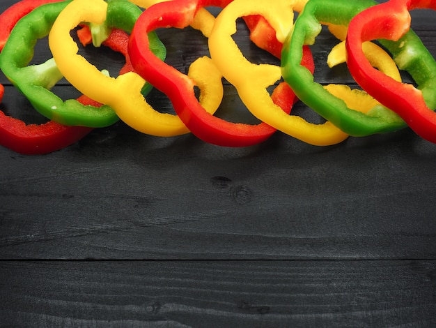 Fresh vegetables, red, yellow, green sweet peppers on dark wood background.