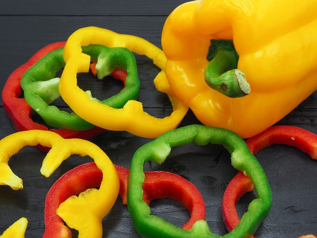 Fresh vegetables, red, yellow, green sweet peppers on dark wood background.