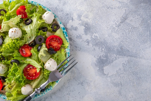 Fresh vegetables salad with tomatoes, mozzarella cheese  and olives. Top view, text space