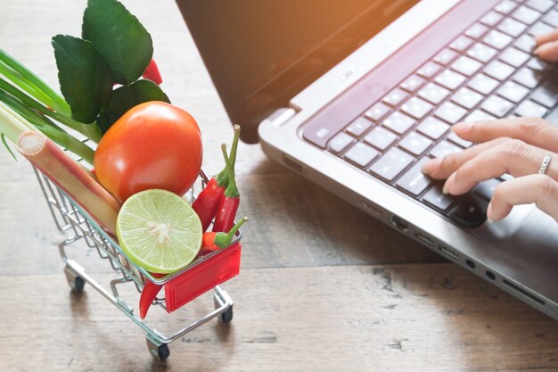 Fresh vegetables in shopping cart with woman using computer, Online shopping, Lifestyle co