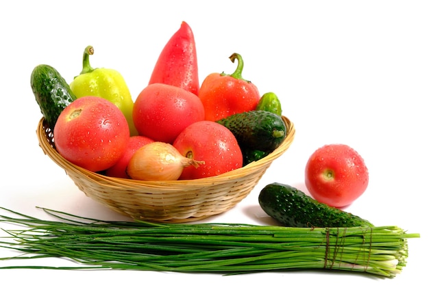 新鮮な野菜の甘いピーマン、きゅうり、トマト、玉ねぎのバスケットの白い背景。